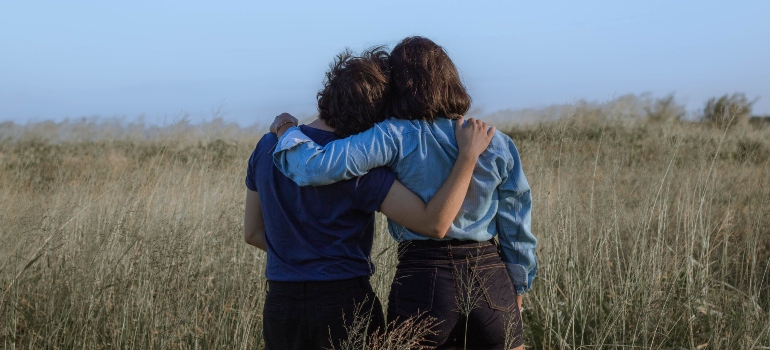 Two women hugging while standing in the field together