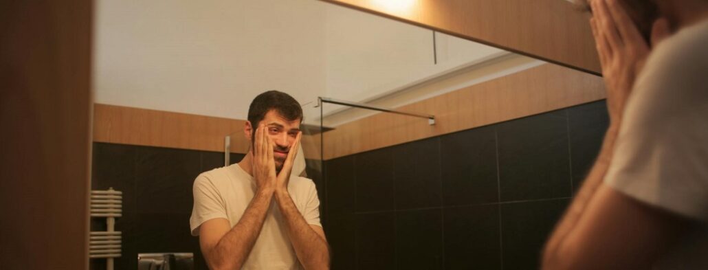 Tired man looking in mirror in bathroom
after having a nocturnal panic attack.