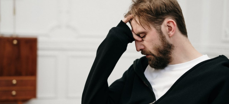 Man holding his head and looking upset while thinking how to overcome the stigma of mental illness