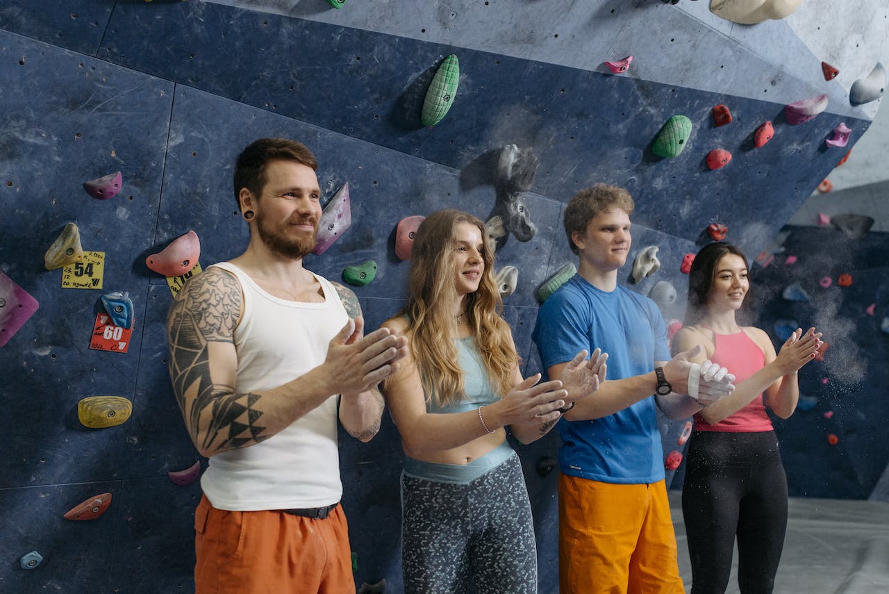 Four young people standing in front of a climbing wall while exploring hobbies and activities for mental health and wellness