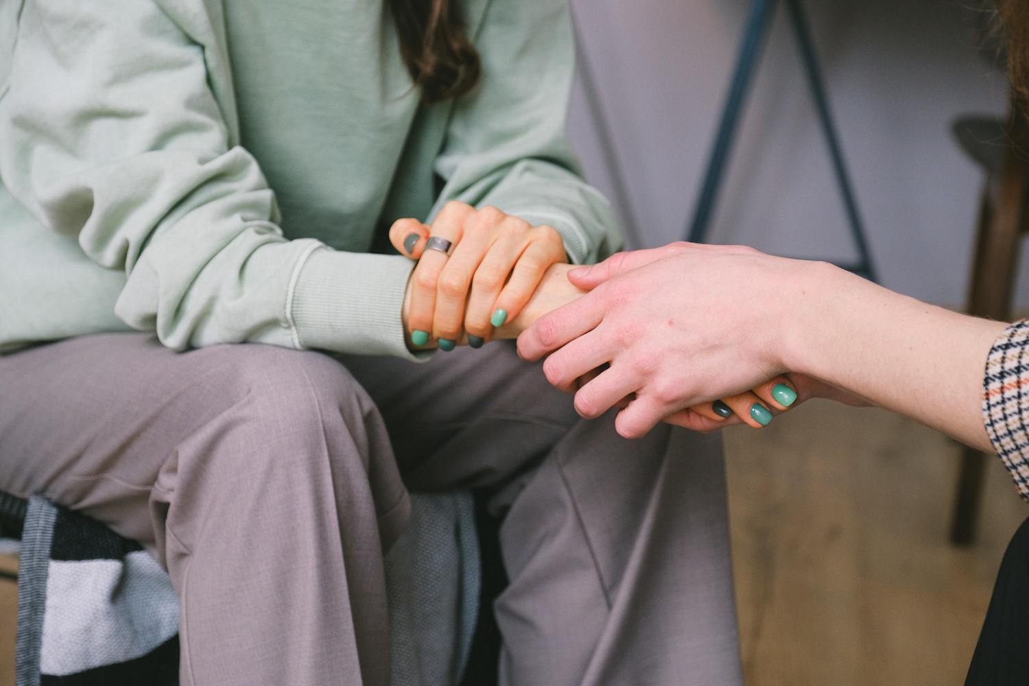 Two women holding hands in support. 