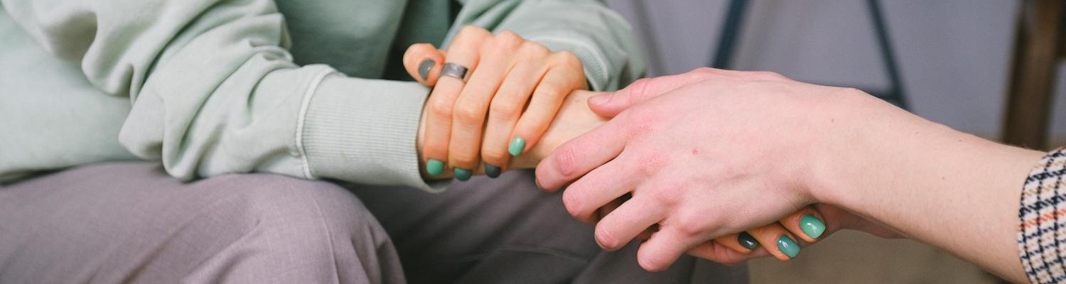 A therapist and a client holding hands while addressing bing drinking and depression issues. 